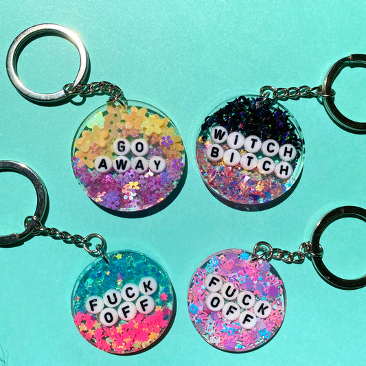 Whimsical Glitter Key Chains. Handmade with epoxy resin, glitter, and clay charms. Chain Color: Silver. Choose from "Go away" "witch bitch" or "fuck off"